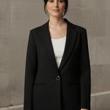 Woman wearing a black blazer over a white shirt with a neutral background