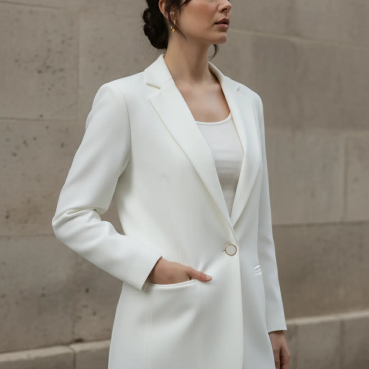 Woman wearing a white blazer against a beige wall