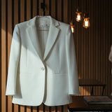 White blazer hanging on a wooden wall with a blurred background