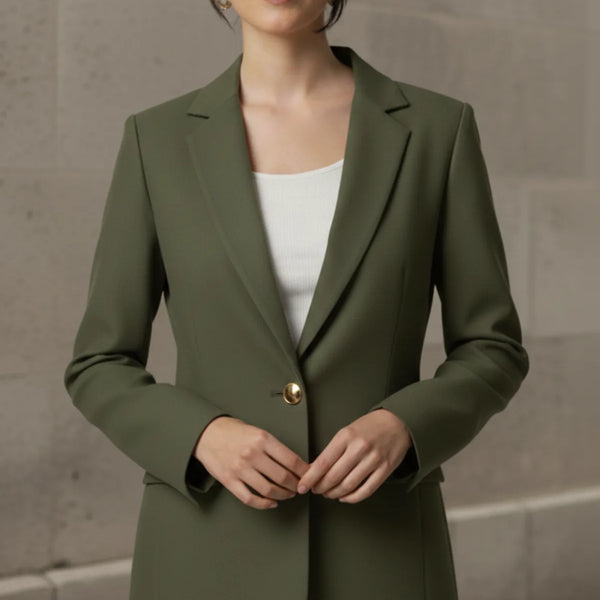 Woman wearing an olive blazer over a white top against a neutral background