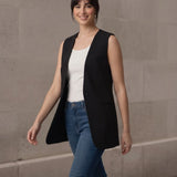 Woman walking confidently towards the camera in a stylish black sleeveless blazer, showcasing the garment's comfortable fit and movement.