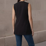 Back view of a woman wearing a tailored black sleeveless vest, showcasing the clean back seams, structure, and longline length.