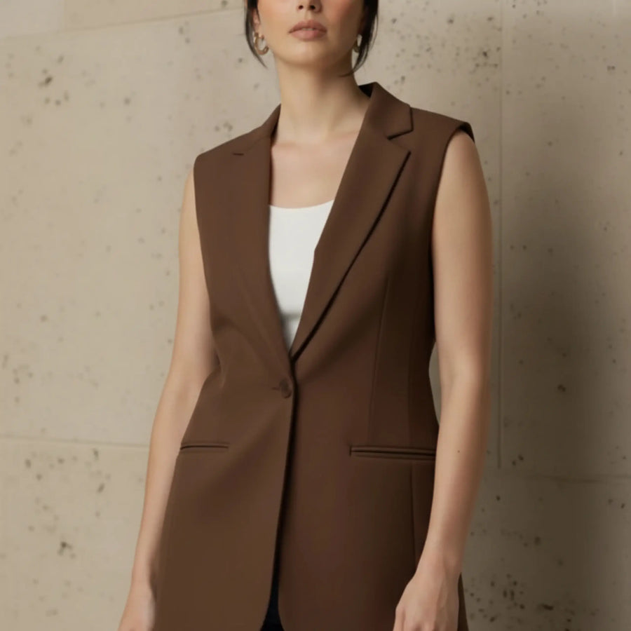 Close-up front view of a chic brown sleeveless tailored vest featuring a classic lapel and single button closure, worn over a white neckline.