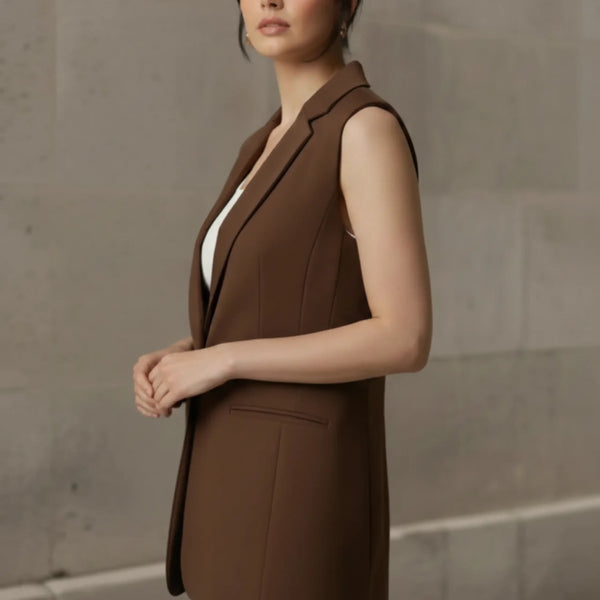 Side angle of a woman wearing a structured brown sleeveless vest, showcasing the elegant drape, comfortable armhole fit, and tailored silhouette.