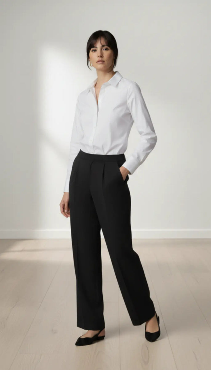 Woman wearing a white shirt and black trouser against a plain background