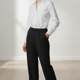 Woman wearing a white shirt and black trouser against a plain background