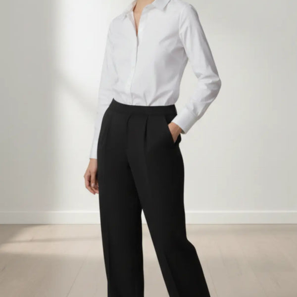 Woman wearing a white shirt and black trouser against a plain background
