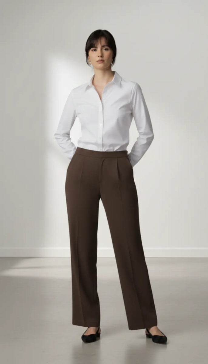 Woman wearing a white shirt and mocha trouser on a plain background