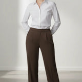 Woman wearing a white shirt and mocha trouser on a plain background