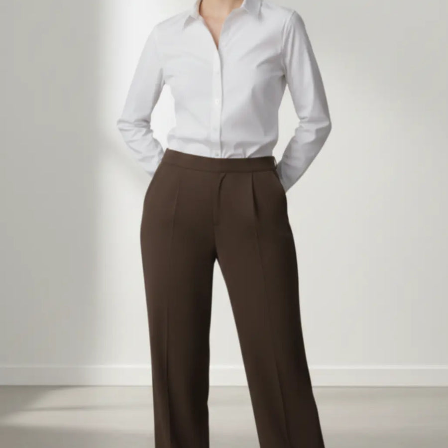 Woman wearing a white shirt and mocha trouser on a plain background