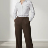 Person wearing a white shirt and mocha trouser on a plain background