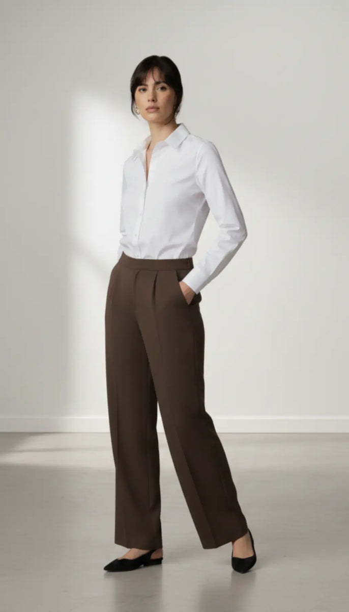 Person wearing a white shirt and mocha trouser on a plain background