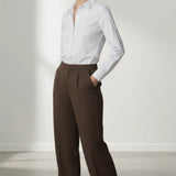 Person wearing a white shirt and mocha trouser on a plain background