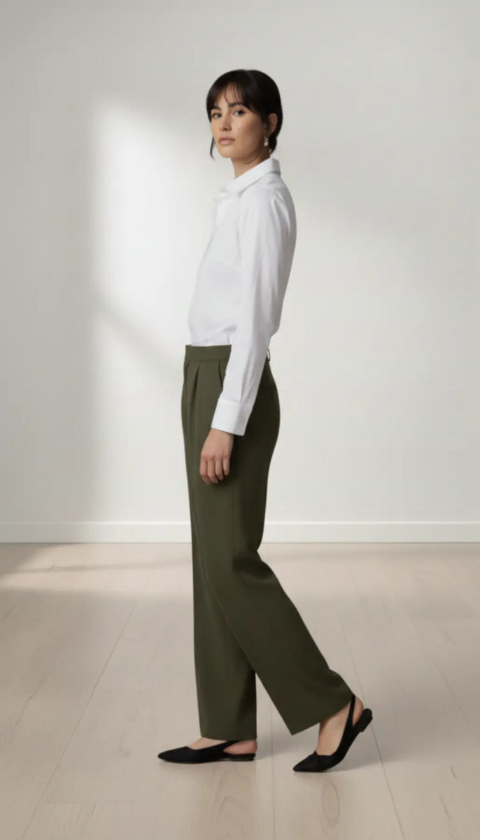 Person wearing a white shirt and olive pants standing against a plain white background