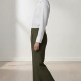 Person wearing a white shirt and olive pants standing against a plain white background