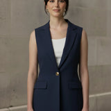 Woman modeling a tailored navy blue sleeveless blazer with a single gold button over a white top