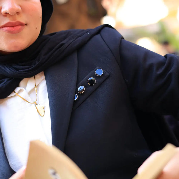 “ZAYTA black tailored blazer on model wearing hijab, showing fabric and inner lining, reading a book outdoors”
