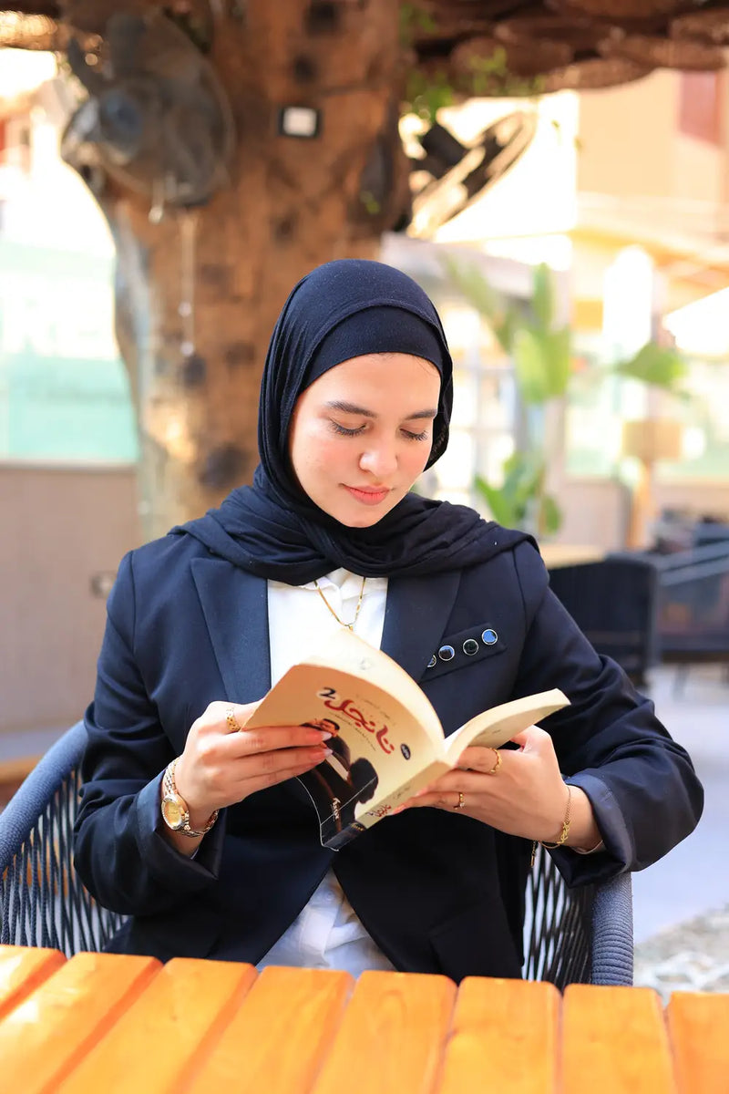 “ZAYTA black women’s blazer on model reading a book outdoors at a table with blurred background”
