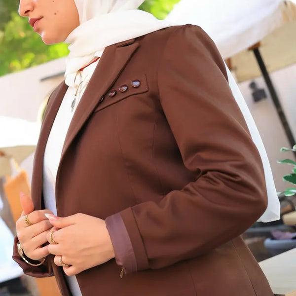 ZAYTA brown tailored blazer on model wearing white hijab, showing fabric and inner lining, outdoor setting
