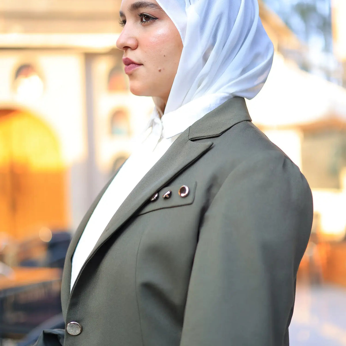 ZAYTA Olive tailored blazer on model wearing white hijab, with a softly blurred background, showcasing fit and premium fabric details
