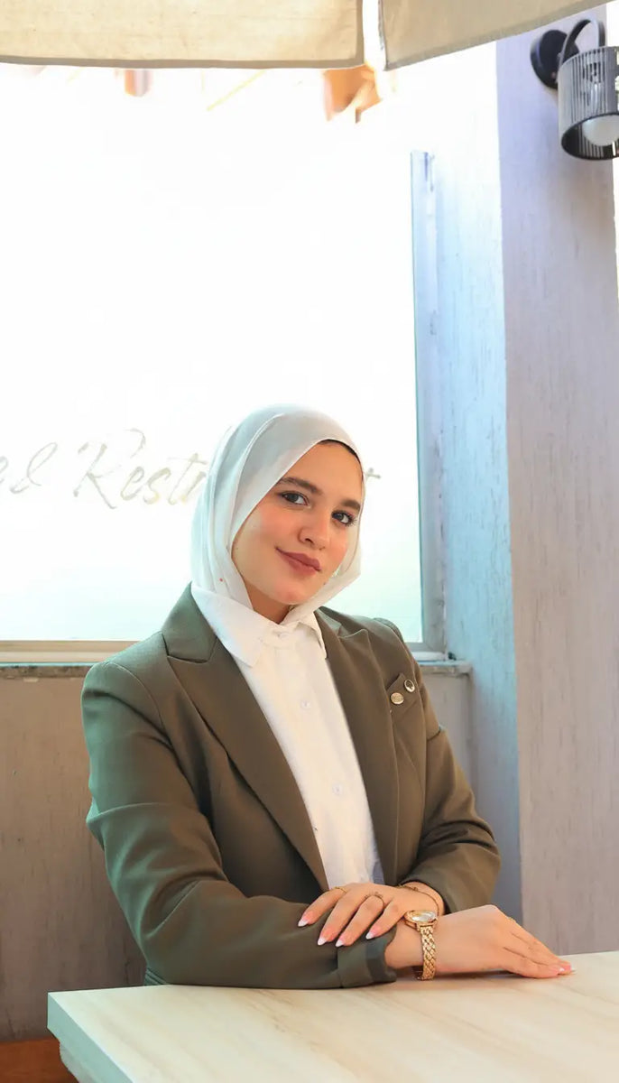ZAYTA formal outfit with olive blazer on model wearing a hijab, sitting at a desk, highlighting tailored fit and professional style