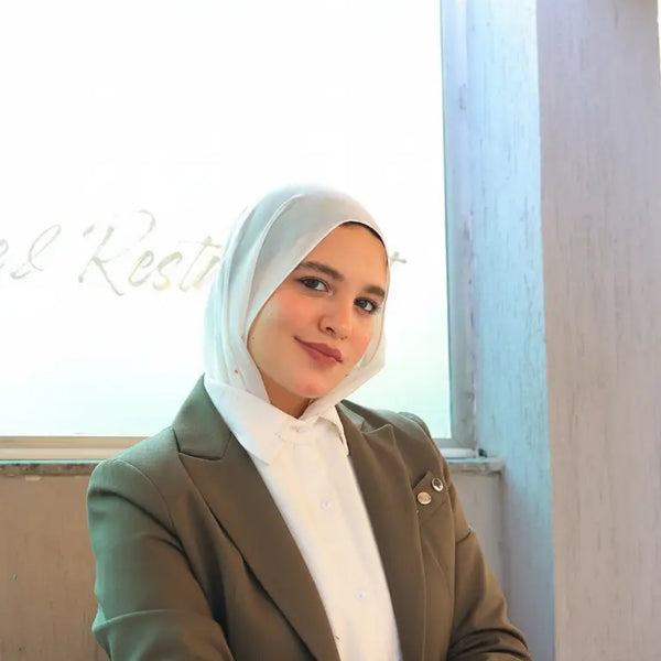 ZAYTA formal outfit with olive blazer on model wearing a hijab, sitting at a desk, highlighting tailored fit and professional style