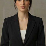 Woman wearing a black blazer over a white top against a neutral background