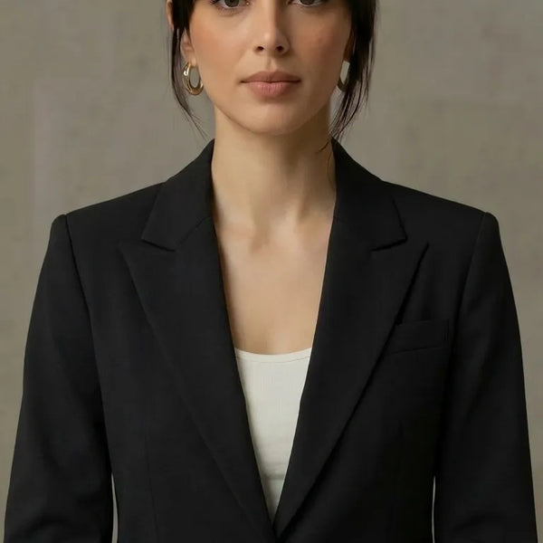 Woman wearing a black blazer over a white top against a neutral background