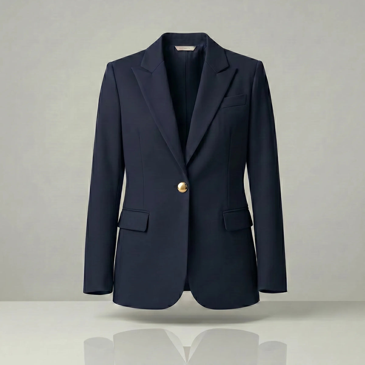 Navy blazer with a gold button on a light gray background