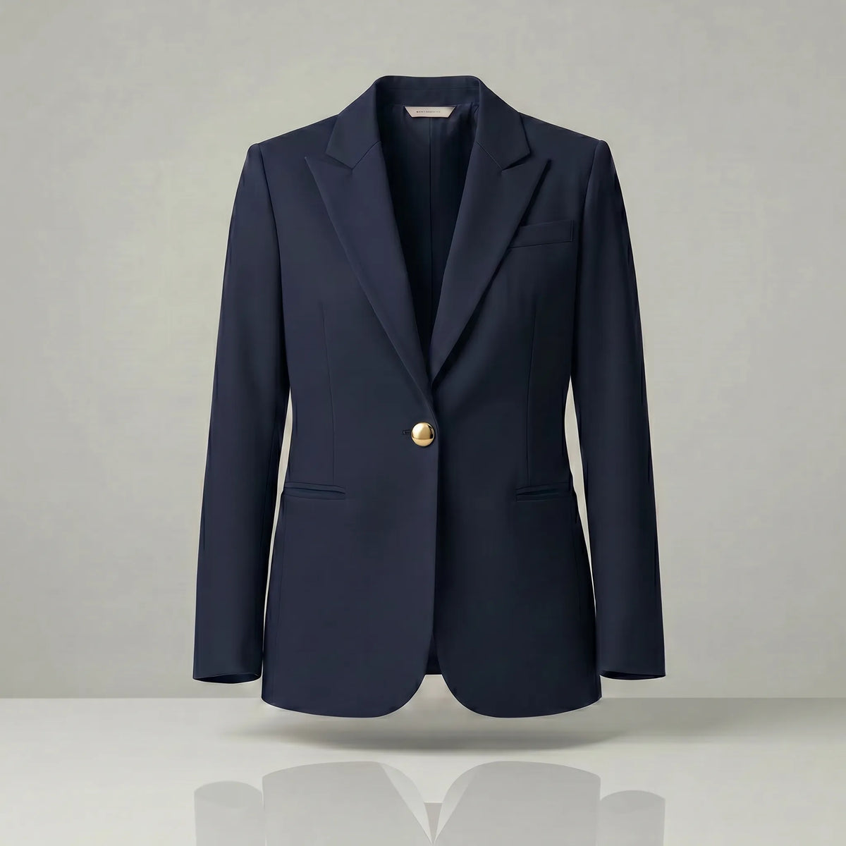 Navy blazer with a gold button on a light gray background