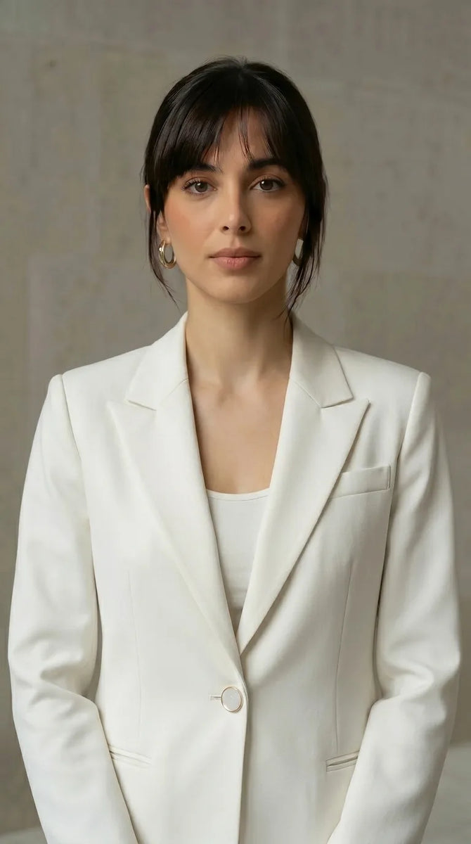 Woman wearing a white blazer against a neutral background