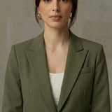 Woman wearing a olive blazer over a white top against a neutral background