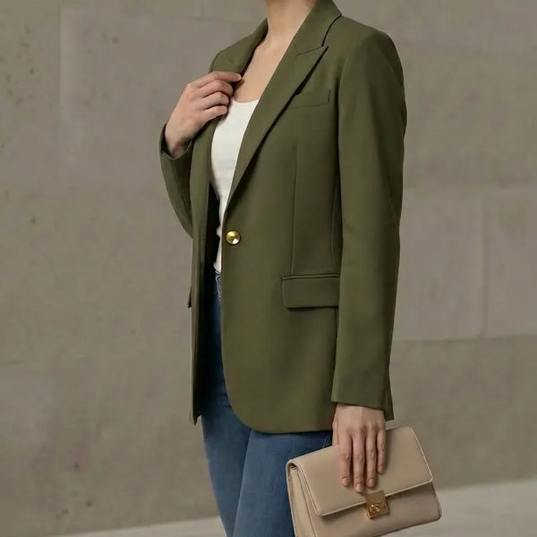 Woman wearing an olive green blazer with a beige clutch against a neutral background