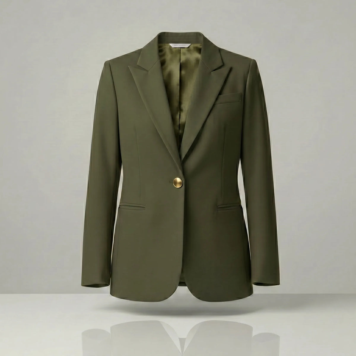 olive blazer with a gold button on a light gray background