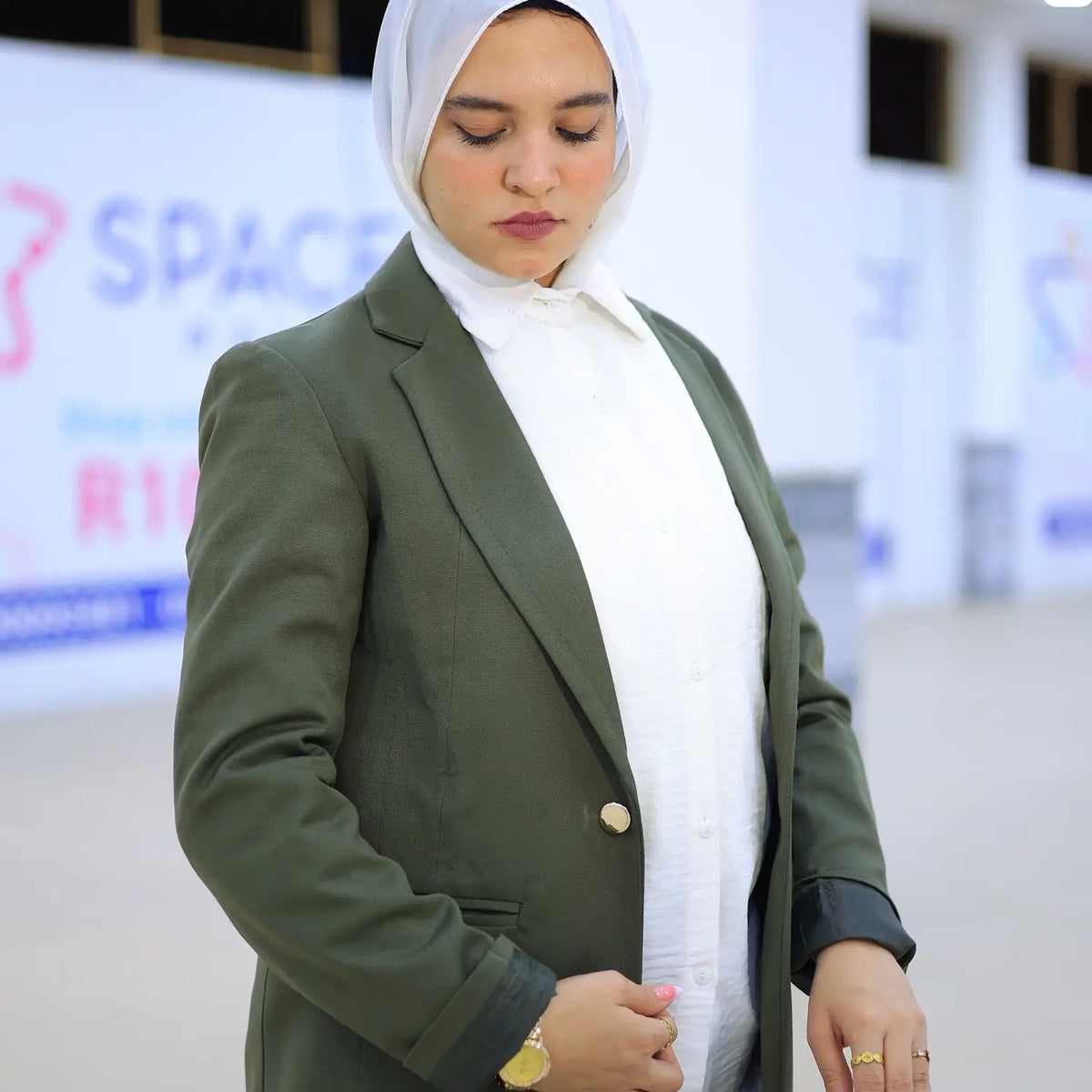 ZAYTA Olive tailored blazer on model wearing white hijab, showing fabric and inner lining, indoor setting
