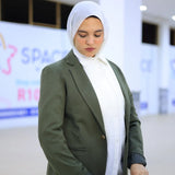 ZAYTA green tailored blazer on model wearing white hijab, showing fabric and inner lining, indoor setting
