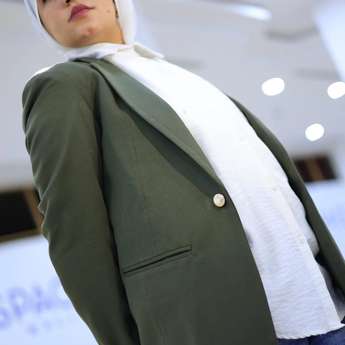 ZAYTA olive tailored blazer on model over white shirt with hijab, showing fabric and inner lining, indoor
