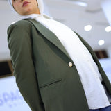 ZAYTA olive tailored blazer on model over white shirt with hijab, showing fabric and inner lining, indoor

