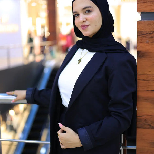 “ZAYTA off white women’s blazer on model wearing black hijab and dark outfit, indoor setting with blurred background”
