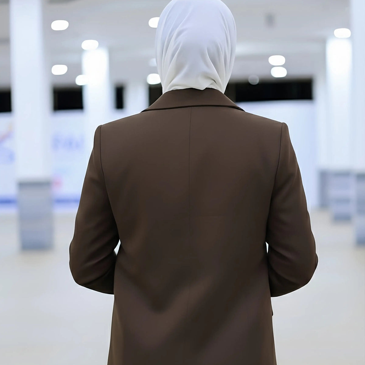 ZAYTA brown tailored blazer on model wearing white hijab, showing fabric and inner lining, indoor setting
