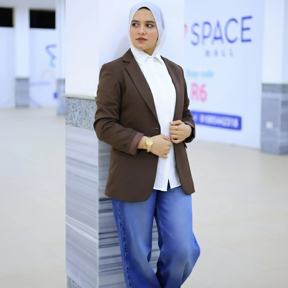 ZAYTA brown tailored blazer on model over white shirt and blue jeans, showing fabric and inner lining, indoor setting with blurred background
