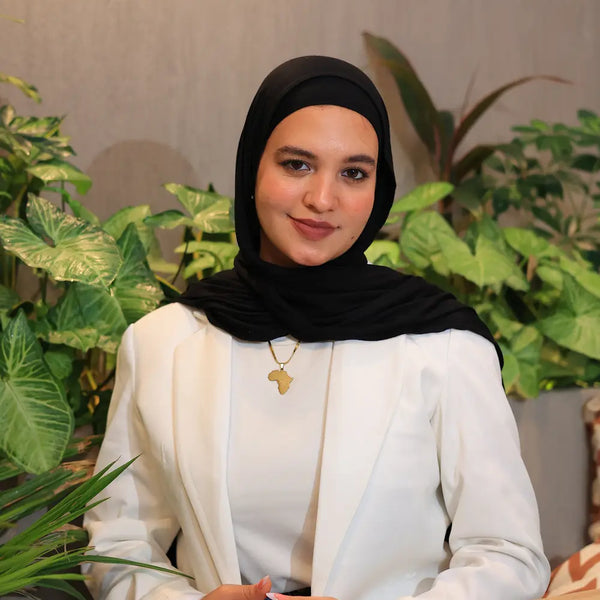 “ZAYTA off white women’s blazer on model wearing black hijab, tailored fit, sitting in a room with plants”