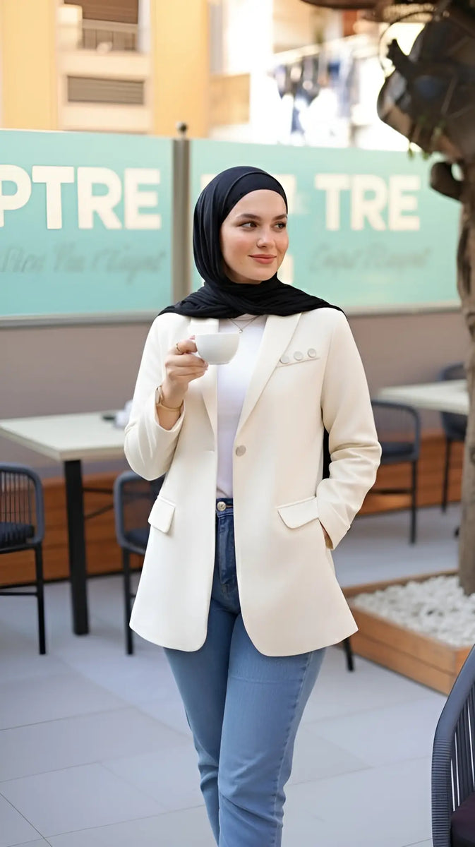 ZAYTA Of-White tailored blazer on model wearing black hijab, showing fabric and inner lining, holding a phone in casual setting