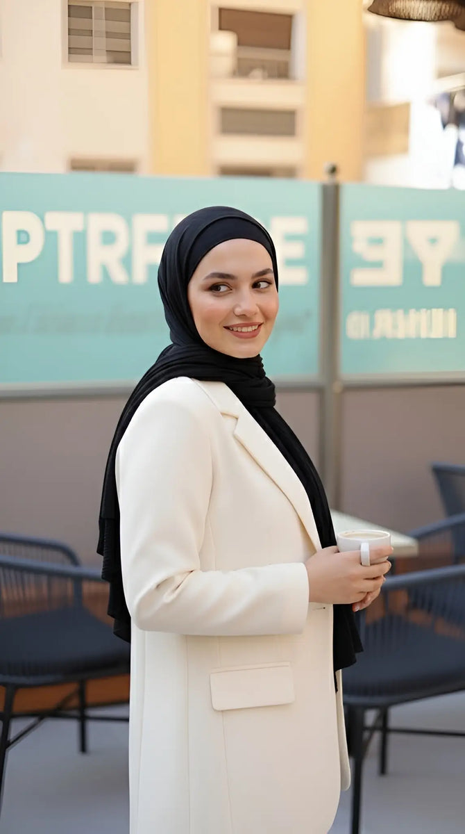 ZAYTA off-white tailored blazer on model wearing black hijab, showing fabric and inner lining, standing outdoors with blurred background