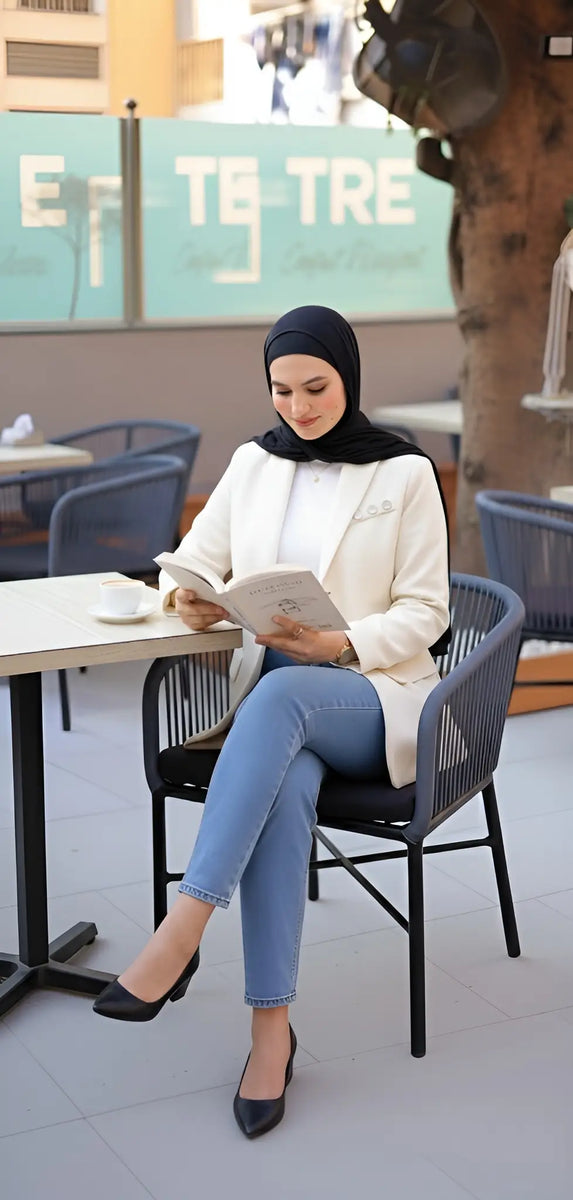 ZAYTA tailored blazer on model wearing hijab, showing fabric and inner lining, reading a book in modern cafe setting