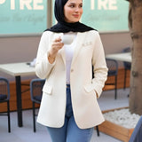 ZAYTA Off-white tailored blazer on model wearing black hijab, showing fabric and inner lining, standing outdoors with blurred background