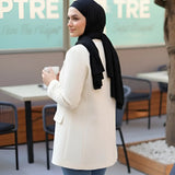 ZAYTA tailored blazer on model wearing hijab, showing fabric and inner lining, holding a coffee cup in outdoor cafe setting